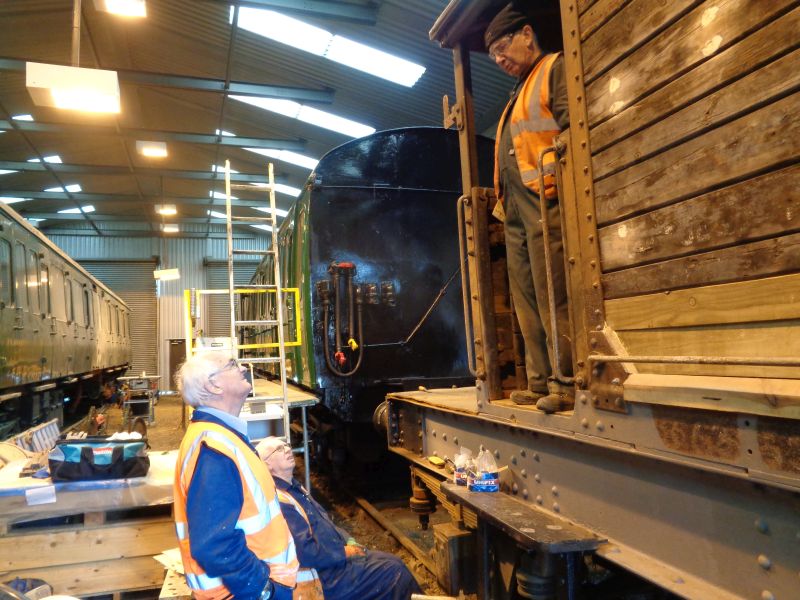 Geoff Horner takes a break from cleaning up the running gear and discusses the final internal cabin paint scheme with Patrick and John. The wheels of the barrow can be seen in the mid-distance.brPhotographer David BellbrDate taken 07112019