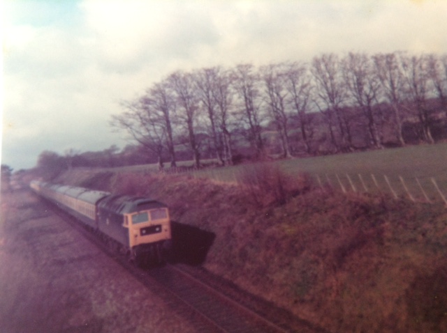 A returning Territorial Army special from Okehampton to Sunderland worked by a class 47 loco with 10 MK I coaches, seen between North Tawton and Bow near Halse Moor, March 1977.brPhotographer Tony HillbrDate taken 00031977