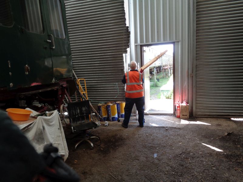 John Coxon captured trying unsuccessfully alas to align slats on the damaged roll-up workshop door. There must be an easier and less nerve shattering way John, but we just haven't thought of one yet.brPhotographer David BellbrDate taken 10052018