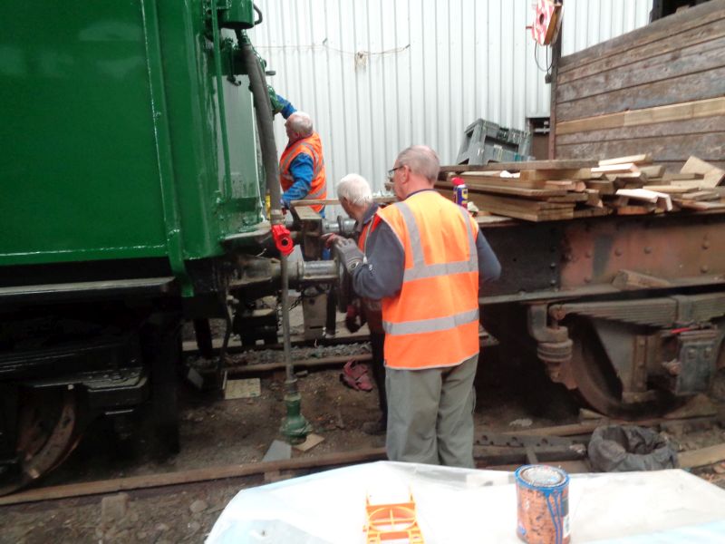 Jon Coxon and Ron Kirby attempt to release the screw coupling between the Thumper and brake van with the aid of copious squirts of WD40. Meanwhile Alan Harris applies a few colourful touches of paint to the braking system.brPhotographer David BellbrDate taken 18102018