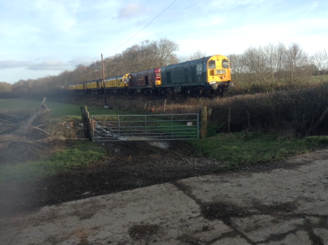The 0529 Derby Railway Technical Centre to Okehampton 6Z01 worked by locos 20189 and 20142 from Exeter, conveying a five vehicle Loram Railgrinder. Seen here cautiously approaching Buttisland farm level crossing just west of Bow. The train had been worked by 56113 to Exeter with the two class 20 locos dead on the rear. brPhotographer Tony HillbrDate taken 09012019