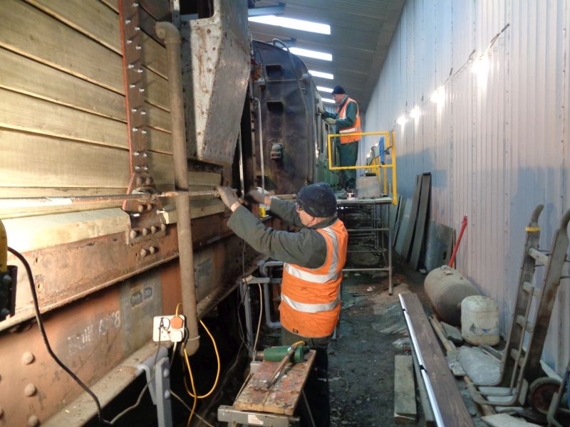 John Davis using a heat gun and scraper on the handrails of the brake van, whilst in the background Nigel Green applies grey undercoat to the thumper.brPhotographer David BellbrDate taken 10012019