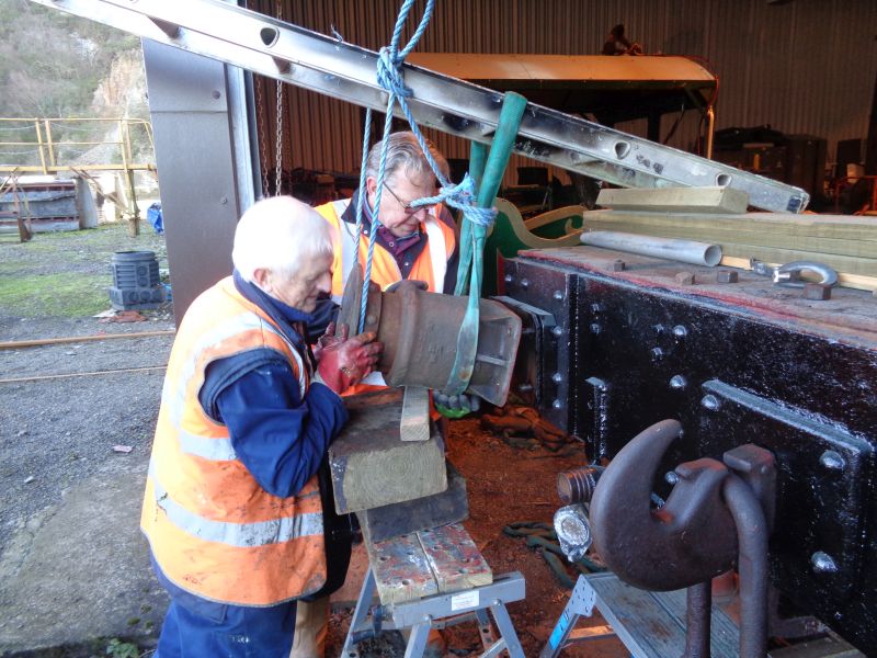 Right, said Fred. With a heave or two ...  -  John Coxon and Terry Bridgeman guide the buffer onto the retaining bolts whilst Ron Kirby lifts the supporting ladder.brPhotographer David BellbrDate taken 17012019