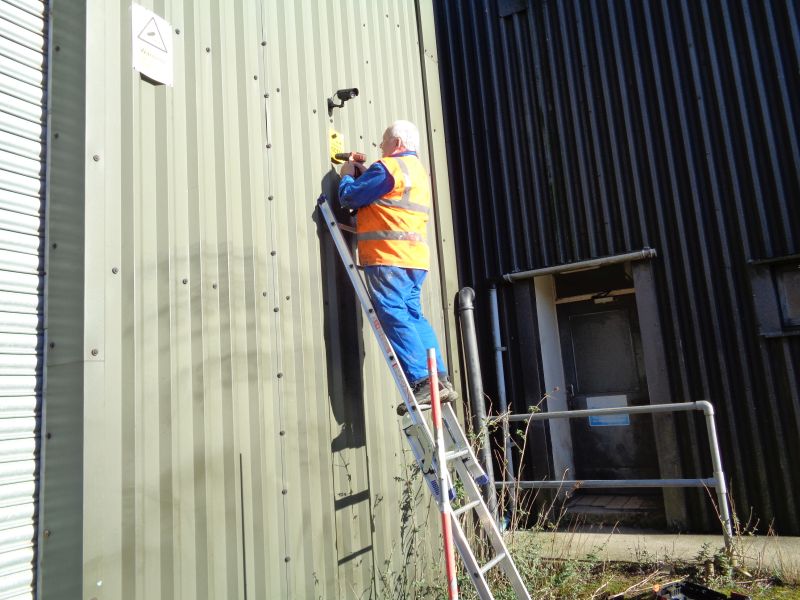 Alan Harris in the warm sunshine fixing the CCTV camera warning signs.brPhotographer David BellbrDate taken 14022019