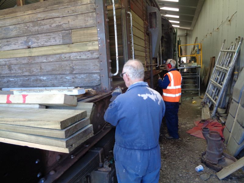 Phil Hull and Patrick Doyle chipping rust and paint. Note the guard's stove on the ground awaiting attention. Chipping and priming the North side of the mainframe is almost complete.brPhotographer David BellbrDate taken 04072019