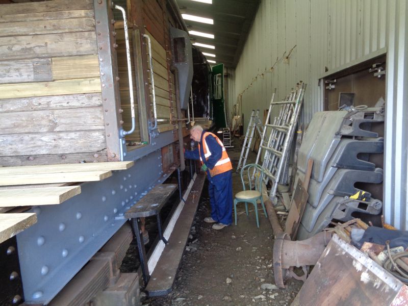 Geoff Horner chipping away at the last of the rust, paint etc. in the area of the brake piping. By the end of day very little remained to do.brPhotographer David BellbrDate taken 10102019