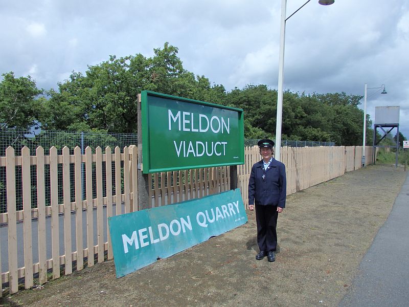 Sue Baxter, the Dartmoor Railway's newest guard, stands alongside the new Meldon running in board.